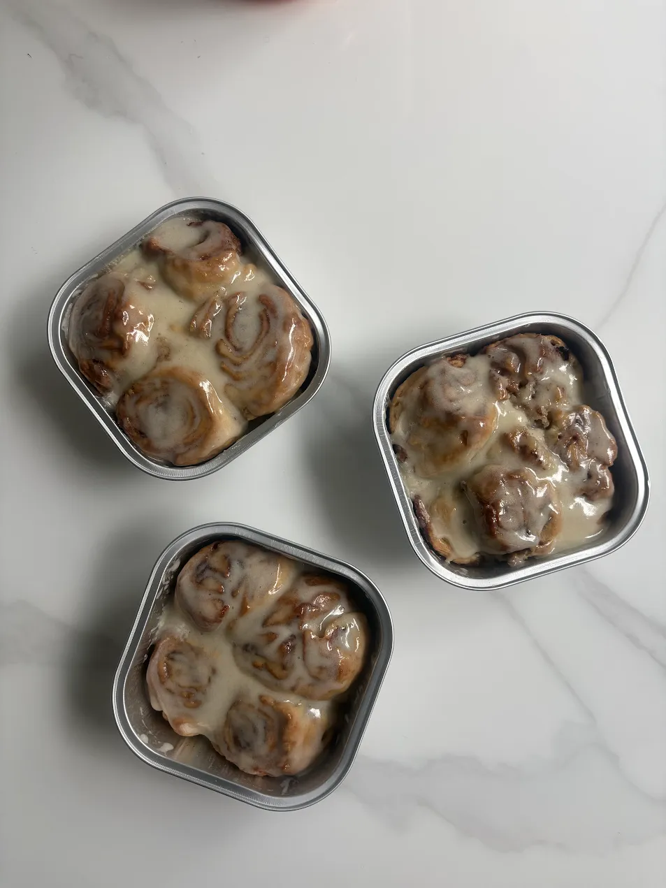 Three trays of glazed cinnamon rolls from the Orielle kitchen.